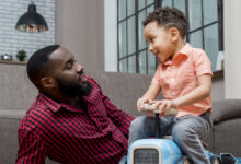 garoto conversando com o pai e dirigindo carro de brinquedo