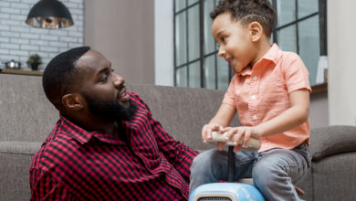 garoto conversando com o pai e dirigindo carro de brinquedo